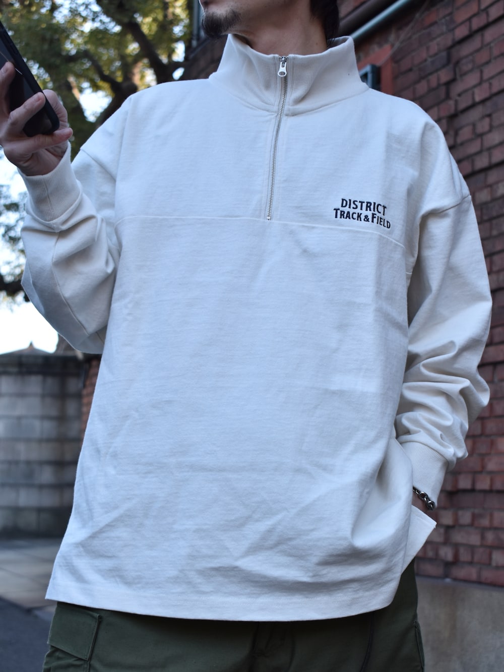 ホワイト系のTシャツ/カットソー、グリーン系のカーゴパンツ、グレー系のスニーカーを着用したメンズの春コーディネートの2枚目の写真