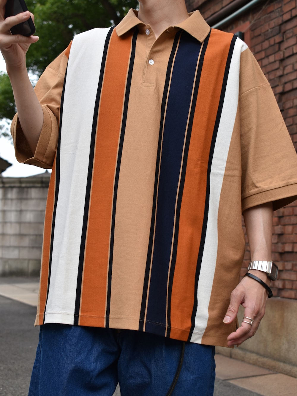 ベージュ系のポロシャツ、ブルー系のデニムパンツ、ブラック系のサンダルを着用したメンズの夏コーディネートの2枚目の写真