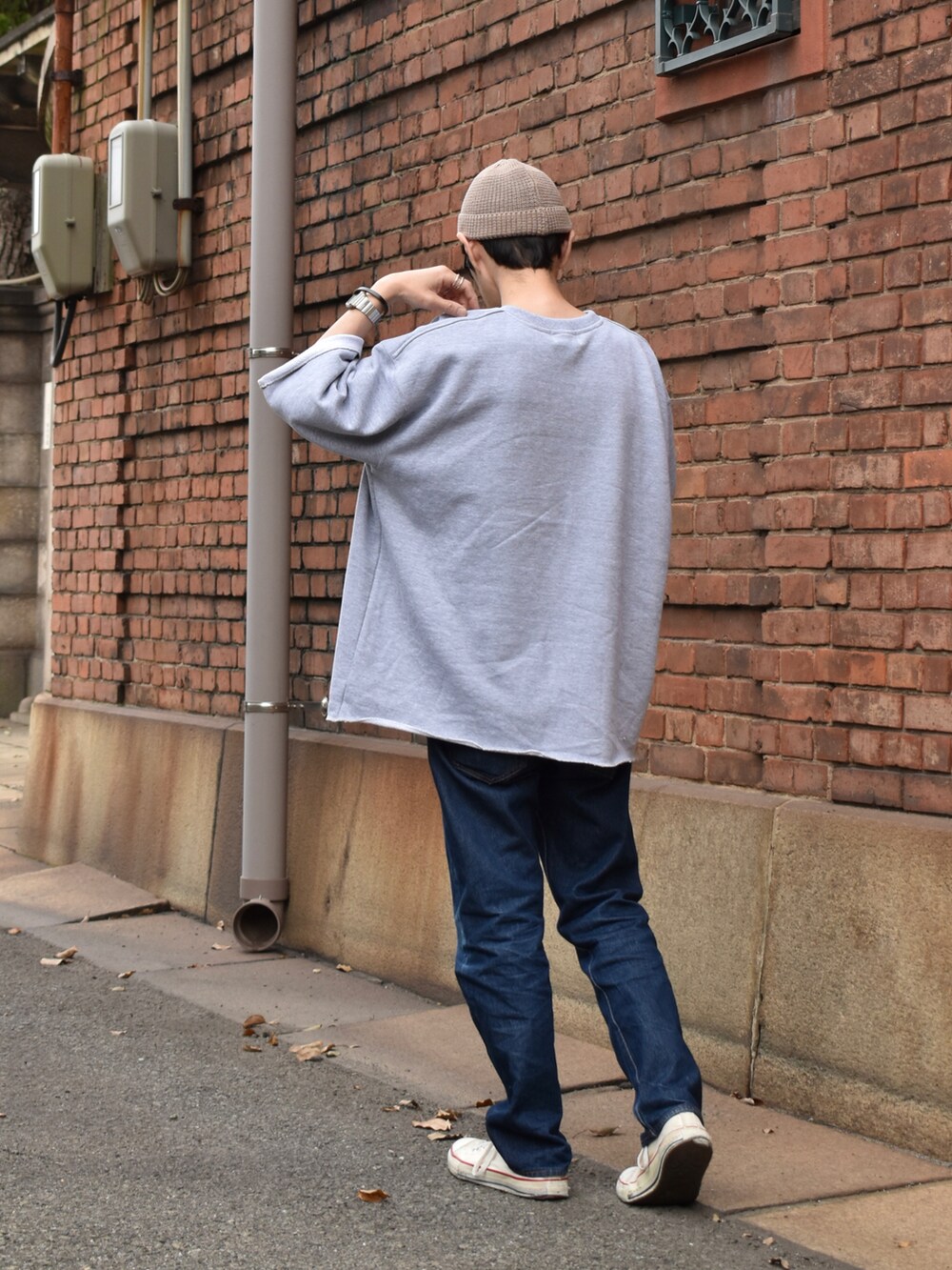 グレー系のスウェット、ブルー系のデニムパンツ、ホワイト系のスニーカーを着用したメンズの春コーディネートの3枚目の写真