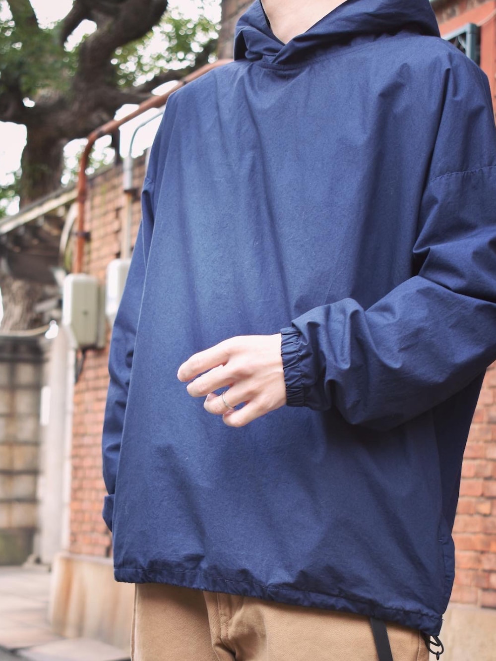 ブルー系のパーカー、ブラウン系のチノパンツ、グレー系のスニーカーを着用したメンズの秋コーディネートの2枚目の写真