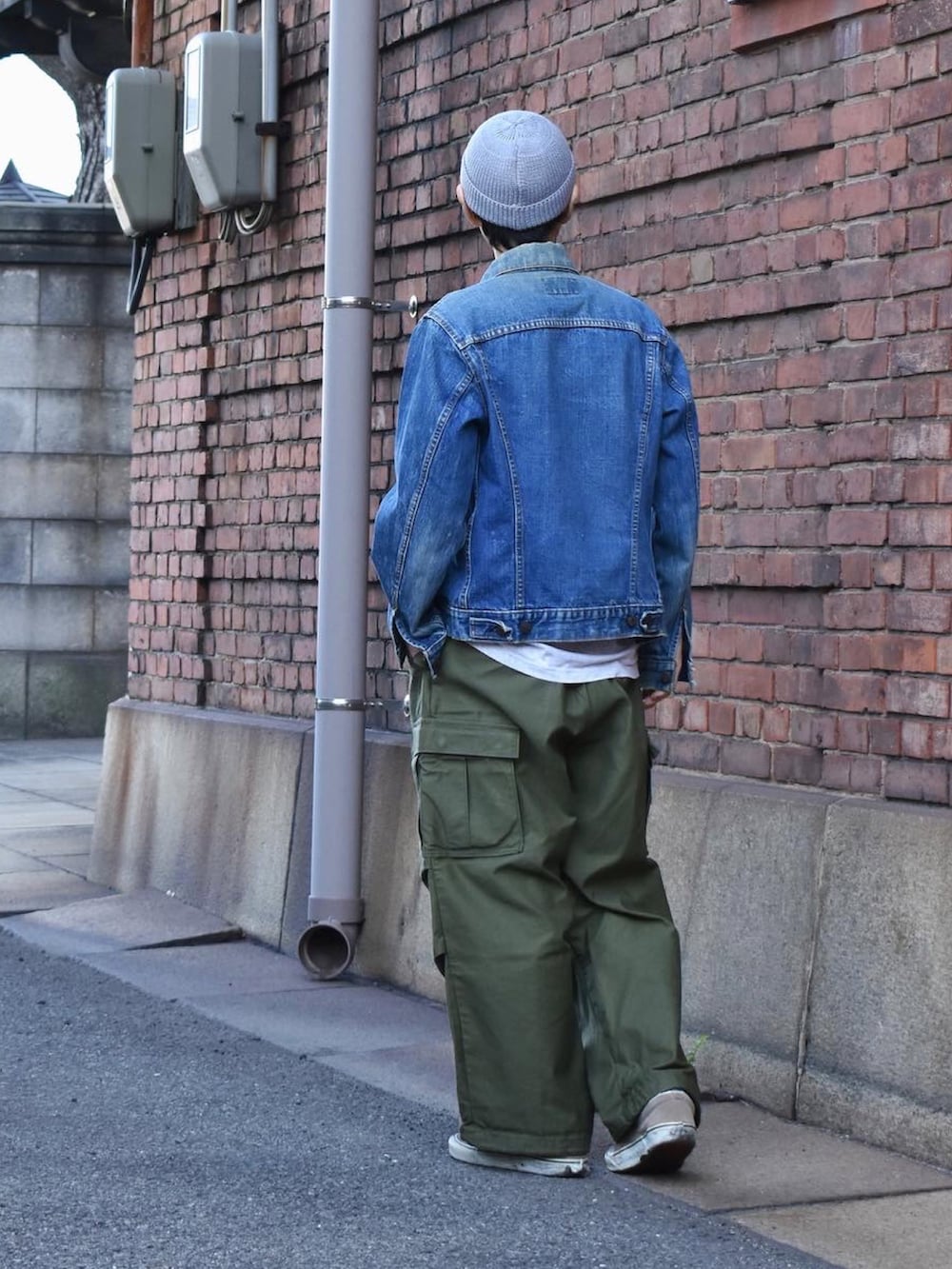 ブルー系のデニムジャケット、グリーン系のカーゴパンツ、グレー系のスニーカーを着用したメンズの春コーディネートの2枚目の写真