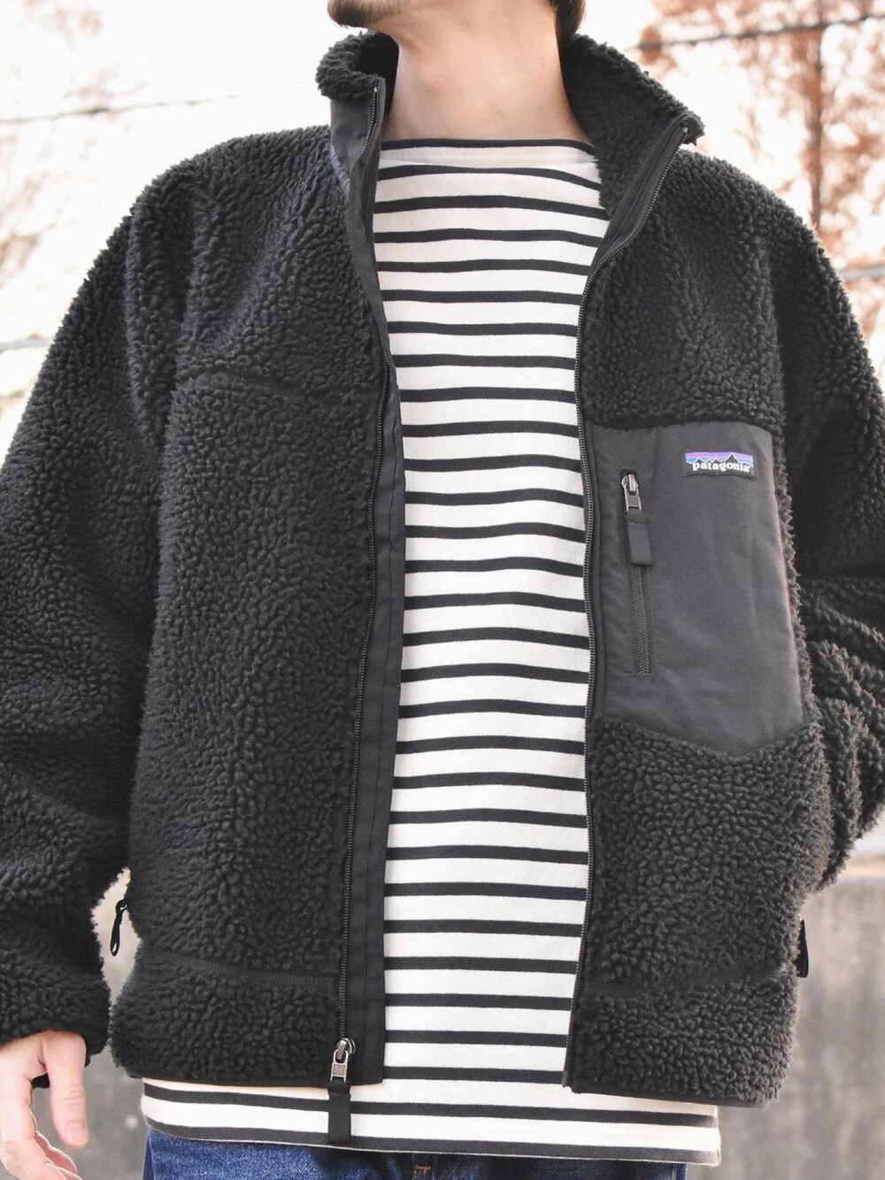 ブラック系のブルゾン、ブラック系のTシャツ/カットソー、ブルー系のデニムパンツを着用したメンズの冬コーディネートの2枚目の写真