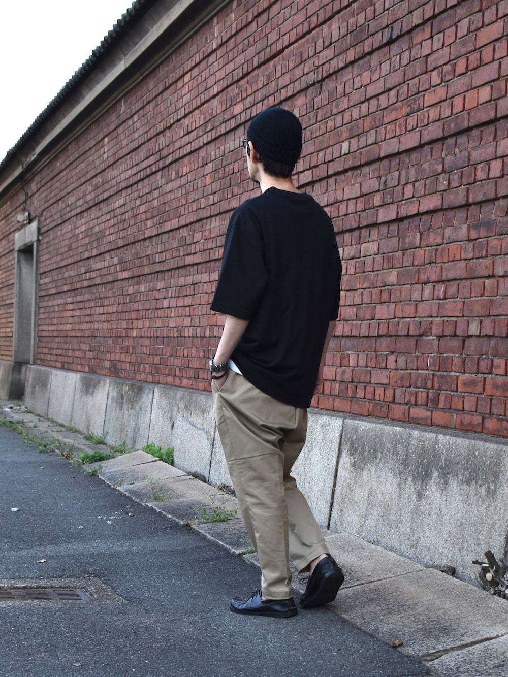 ブラック系のTシャツ/カットソー、ベージュ系のチノパンツ、ブラック系のモカシン/デッキシューズを着用したメンズの春コーディネートの2枚目の写真