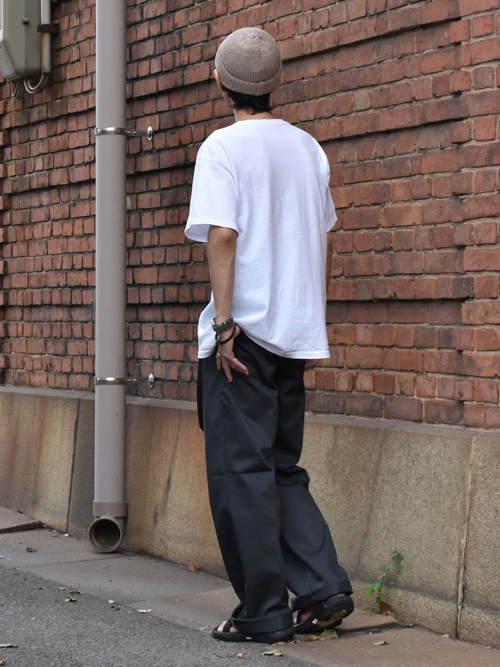 ブラック系のデニムパンツ、ブラック系のサンダル、ベージュ系のニットキャップ/ビーニーを着用したメンズの夏コーディネートの2枚目の写真