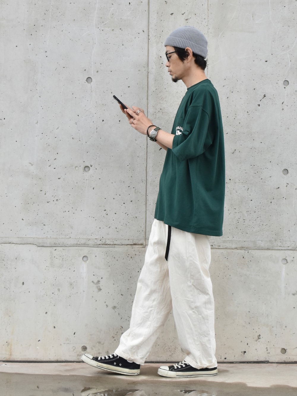 グリーン系のTシャツ/カットソー、ホワイト系のパンツ、ブラック系のスニーカーを着用したメンズの春コーディネートの2枚目の写真