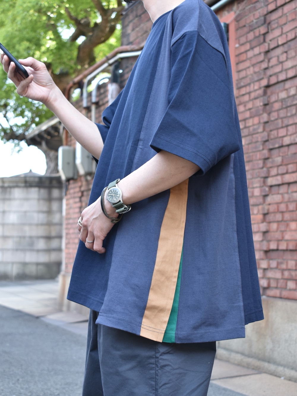 ブルー系のTシャツ/カットソー、グレー系のパンツ、ブラック系のサンダルを着用したメンズの春コーディネートの3枚目の写真