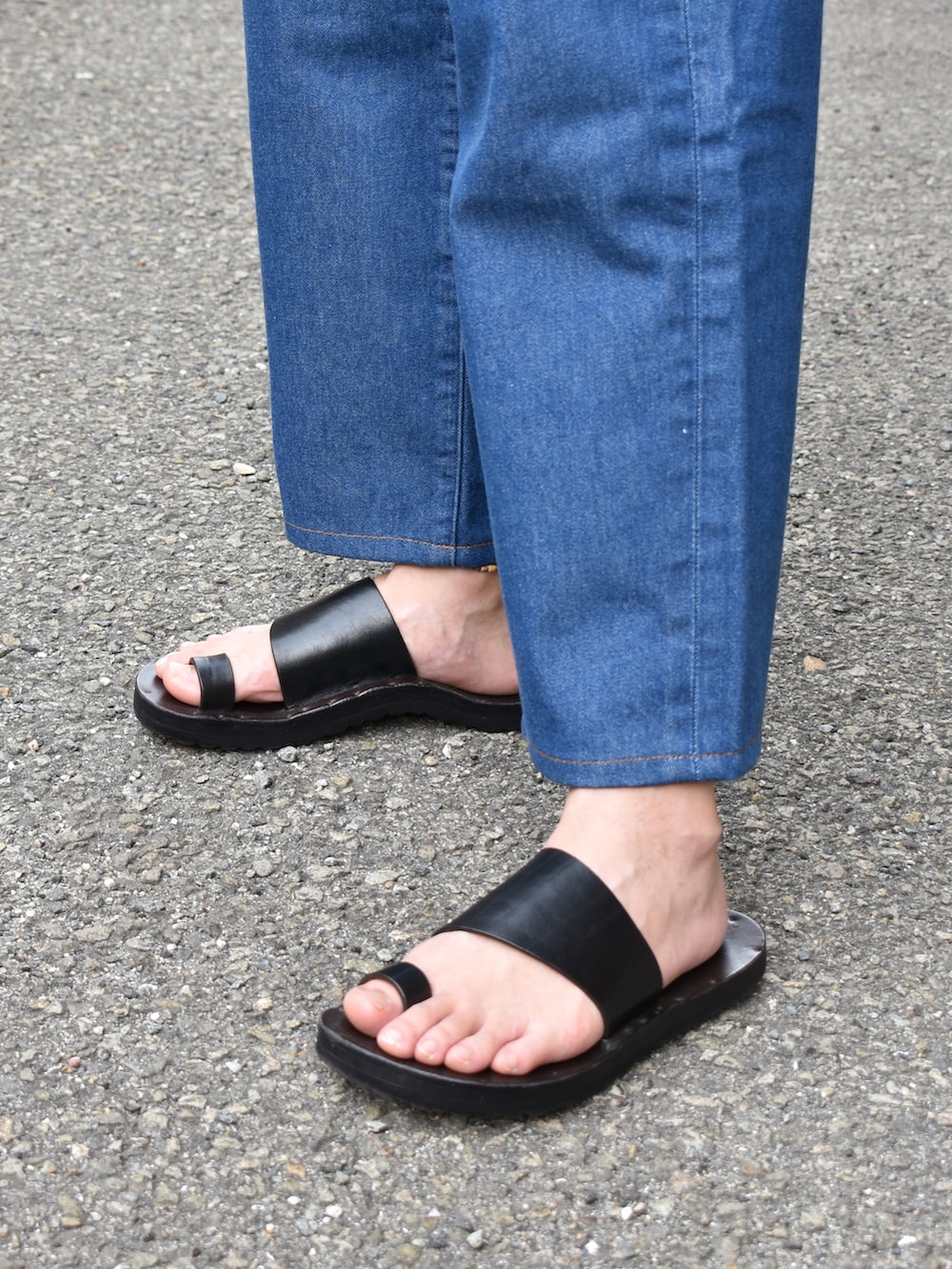 ベージュ系のポロシャツ、ブルー系のデニムパンツ、ブラック系のサンダルを着用したメンズの夏コーディネートの3枚目の写真