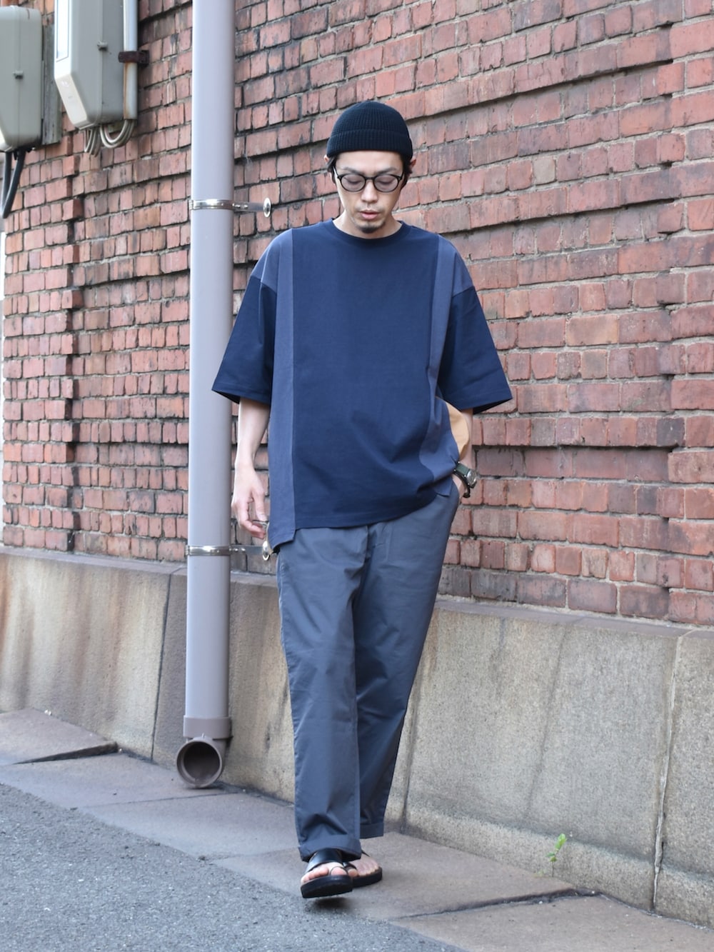 ブルー系のTシャツ/カットソー、グレー系のパンツ、ブラック系のサンダルを着用したメンズの春コーディネートの2枚目の写真