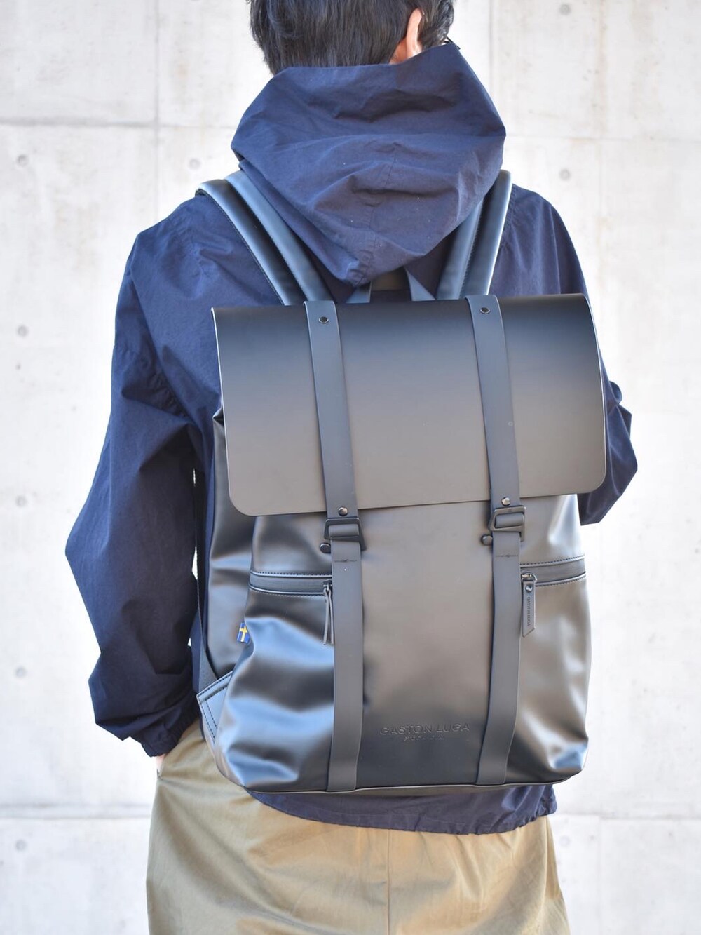 ブルー系のパーカー、グリーン系のチノパンツ、ブラック系のバックパック/リュックを着用したメンズの秋コーディネートの2枚目の写真