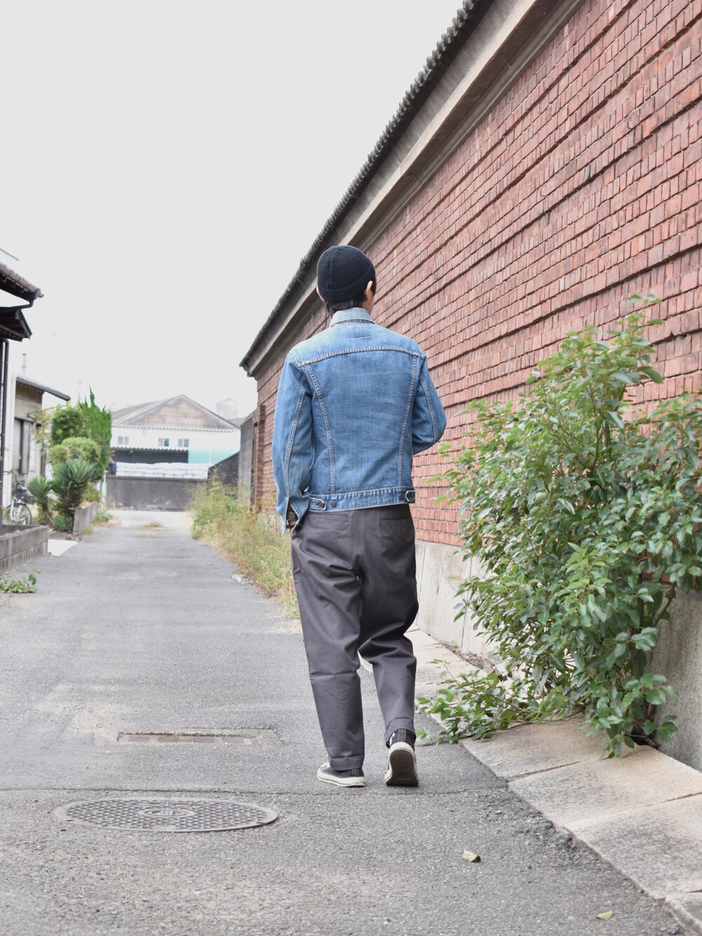 ブルー系のデニムジャケット、グレー系のチノパンツ、ブラック系のスニーカーを着用したメンズの秋コーディネートの2枚目の写真