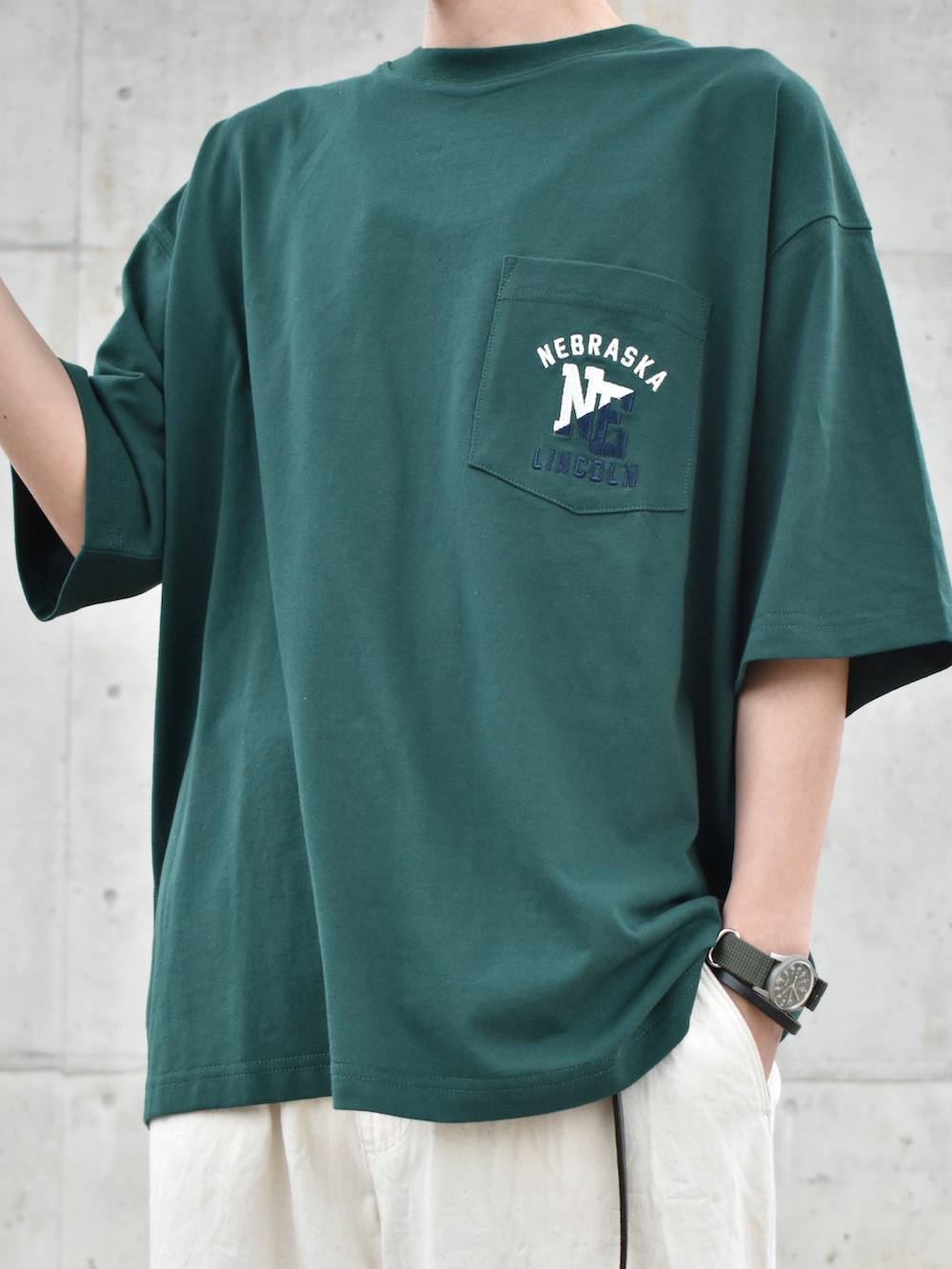 グリーン系のTシャツ/カットソー、ホワイト系のパンツ、ブラック系のスニーカーを着用したメンズの春コーディネートの3枚目の写真