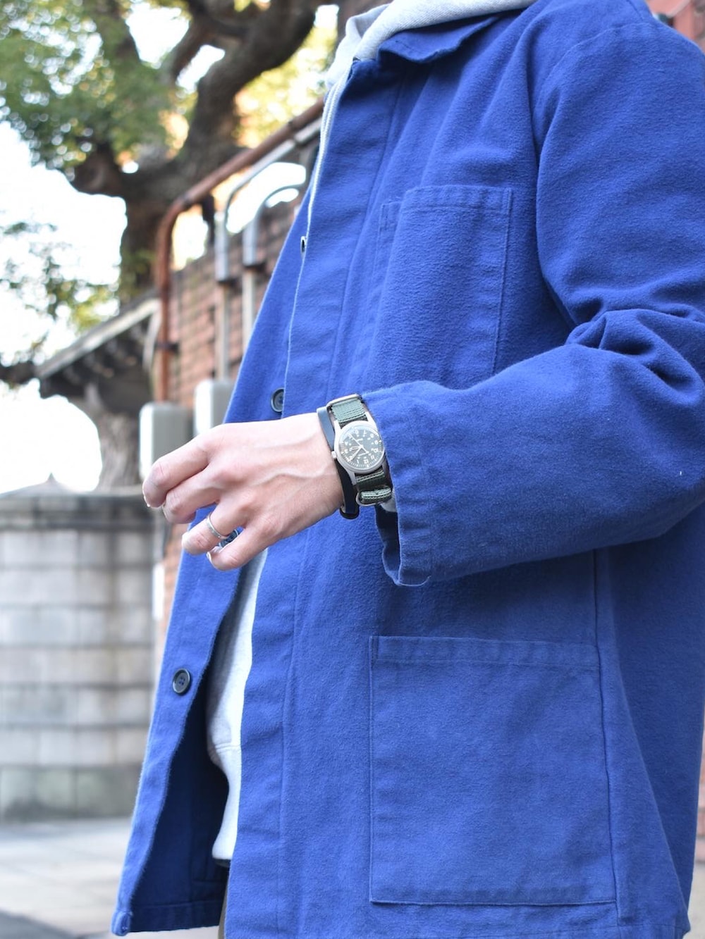 ブルー系のカバーオール、グレー系のパーカー、グリーン系のチノパンツを着用したメンズの秋コーディネートの2枚目の写真