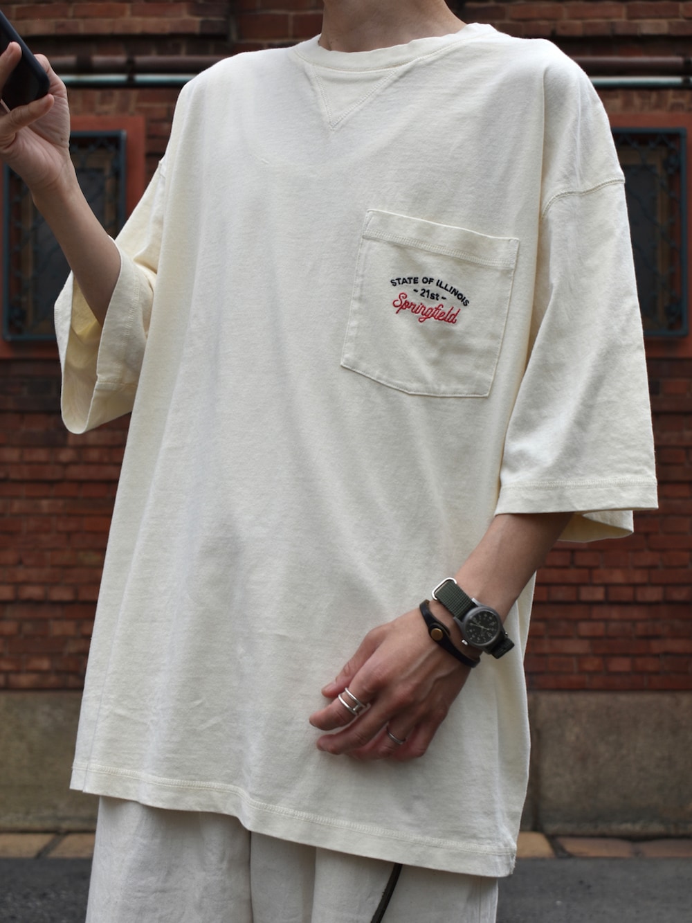 ベージュ系のTシャツ/カットソー、ホワイト系のパンツ、ブラック系のサンダルを着用したメンズの夏コーディネートの2枚目の写真