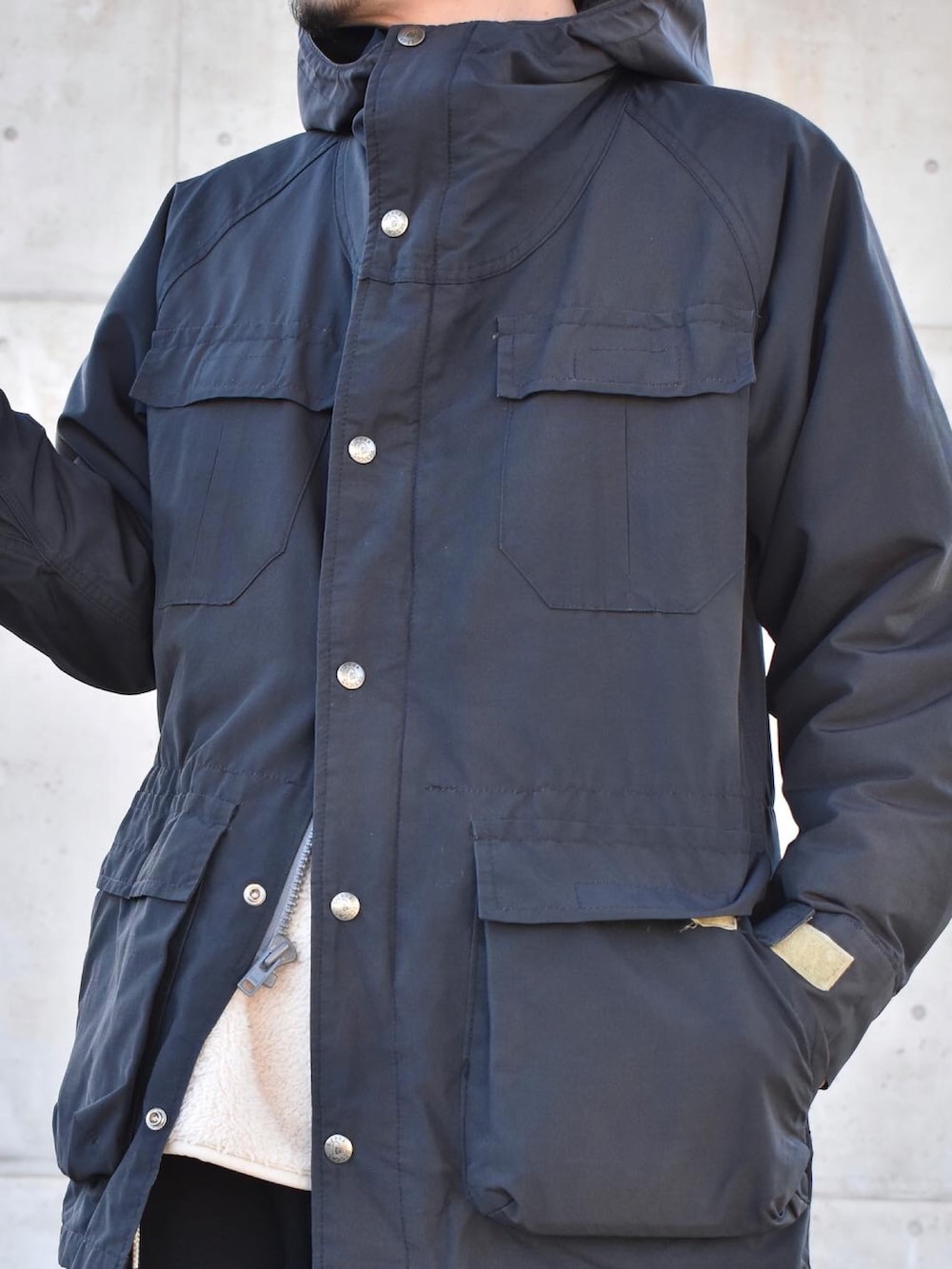 ブラック系のマウンテンパーカー、ホワイト系のTシャツ/カットソー、グレー系のチノパンツを着用したメンズの冬コーディネートの2枚目の写真