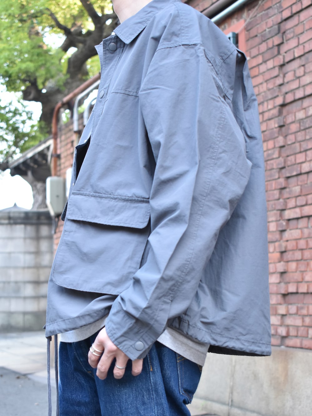 グレー系のブルゾン、ブルー系のデニムパンツ、グリーン系のスニーカーを着用したメンズの春コーディネートの2枚目の写真