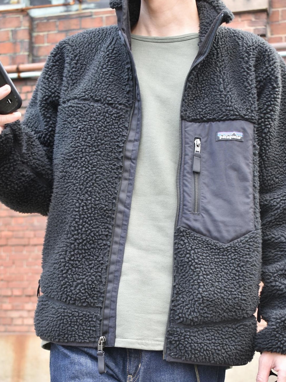 ブラック系のブルゾン、グリーン系のスウェット、ブルー系のデニムパンツを着用したメンズの秋コーディネートの2枚目の写真