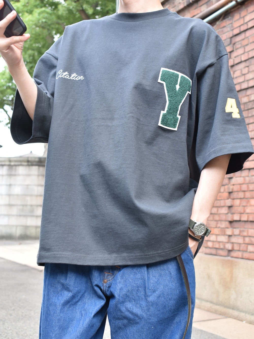 グレー系のTシャツ/カットソー、ブルー系のデニムパンツ、ブラック系のサンダルを着用したメンズの夏コーディネートの2枚目の写真