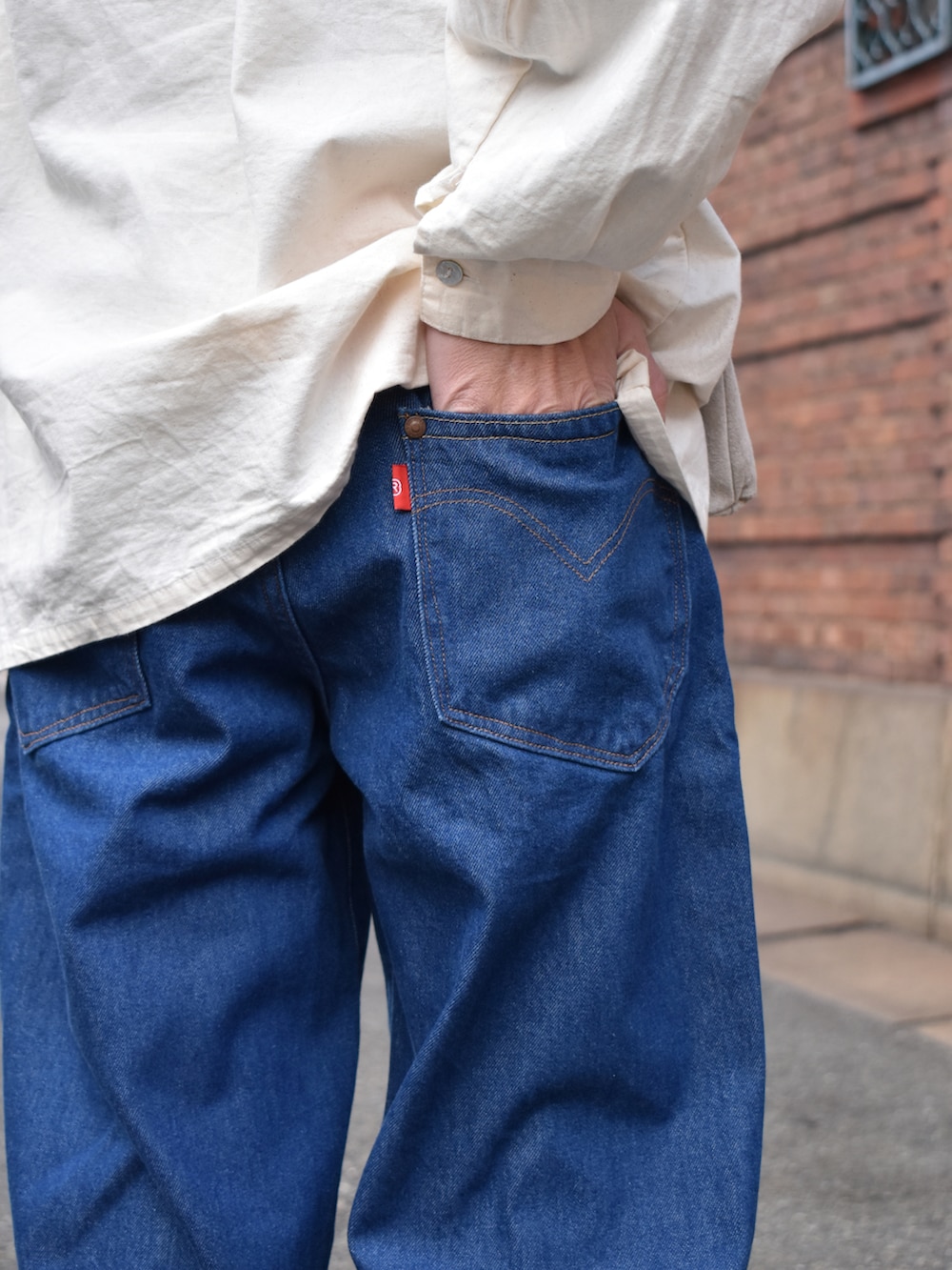 ホワイト系のシャツ/ブラウス、ブルー系のデニムパンツ、ベージュ系のショルダーバッグを着用したメンズの冬コーディネートの2枚目の写真