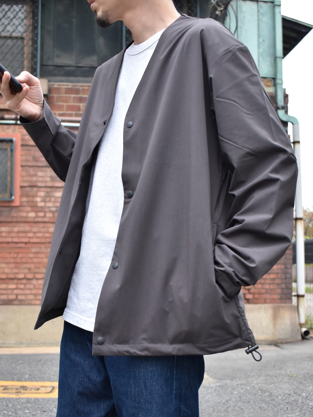 グレー系のカーディガン/ボレロ、ブルー系のデニムパンツ、ブラック系のシューズを着用したメンズの春コーディネートの2枚目の写真