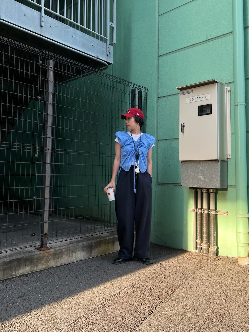 レッド系のキャップを着用したレディースの夏コーディネートの2枚目の写真