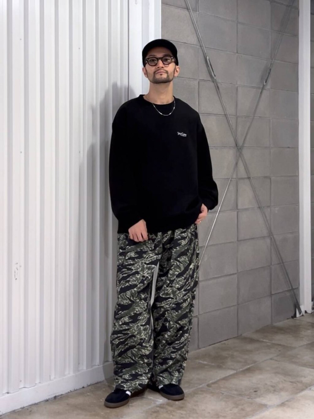 ブラック系のスニーカー、グリーン系のカーゴパンツ、ブラック系のスウェットを着用したメンズの秋コーディネートの2枚目の写真