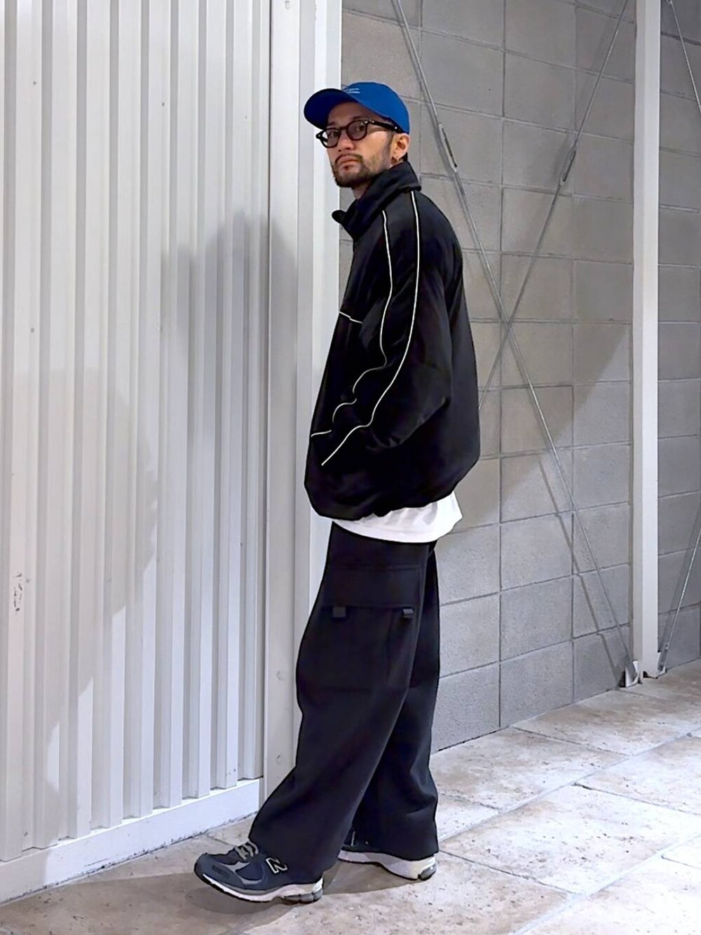 ブラック系のダウンジャケット/コート、ブラック系のスウェットパンツ、ブルー系のキャップを着用したメンズの冬コーディネートの2枚目の写真