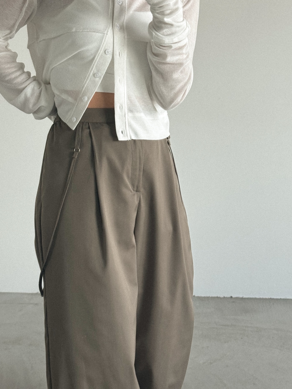 ホワイト系のカーディガン/ボレロ、グレー系のスラックスを着用したレディースの春コーディネートの2枚目の写真