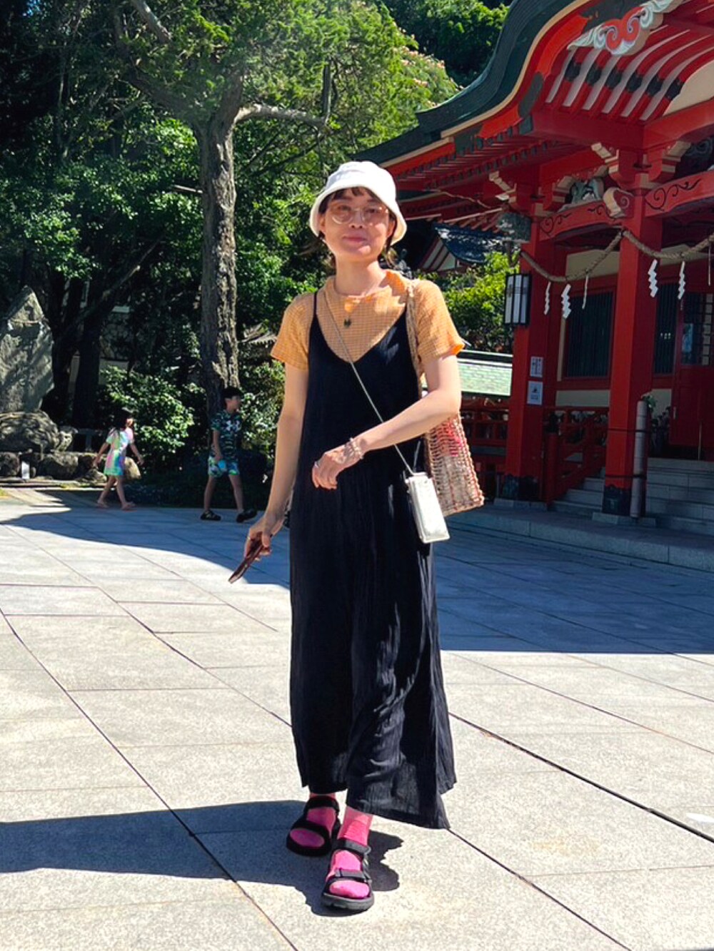 ブラック系のサンダル、オレンジ系のTシャツ/カットソー、ホワイト系のハットを着用したレディースの夏コーディネートの2枚目の写真