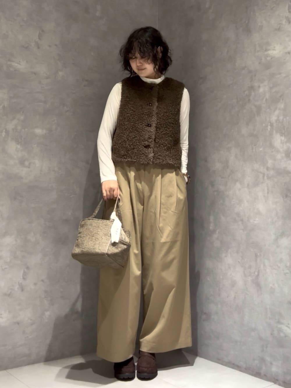 ベージュ系のその他パンツ、ブラウン系のローファー、グリーン系のハンドバッグを着用したレディースの秋コーディネートの2枚目の写真