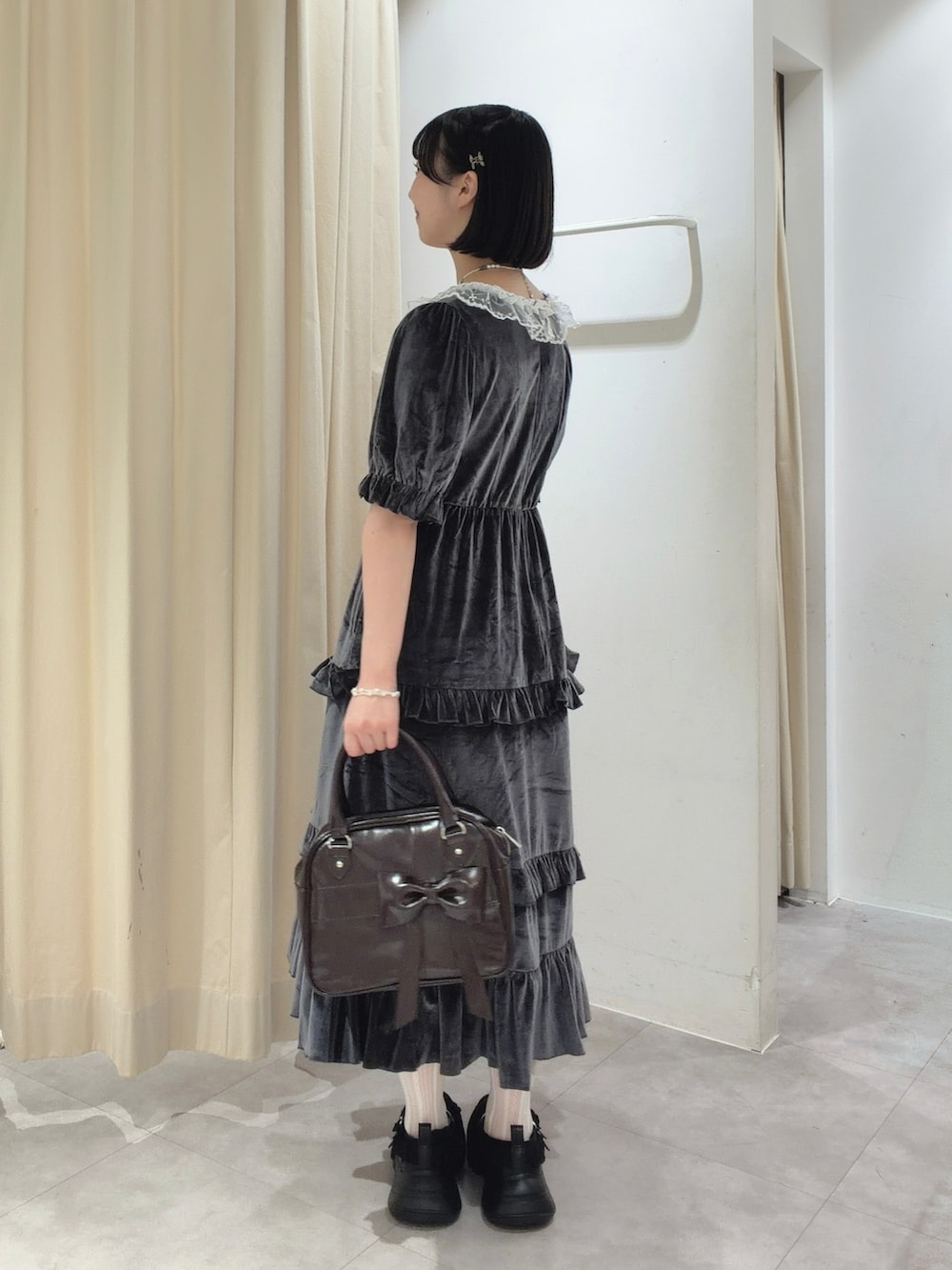 グレー系のワンピース、ブラウン系のハンドバッグ、ブラック系のスニーカーを着用したレディースの夏コーディネートの3枚目の写真