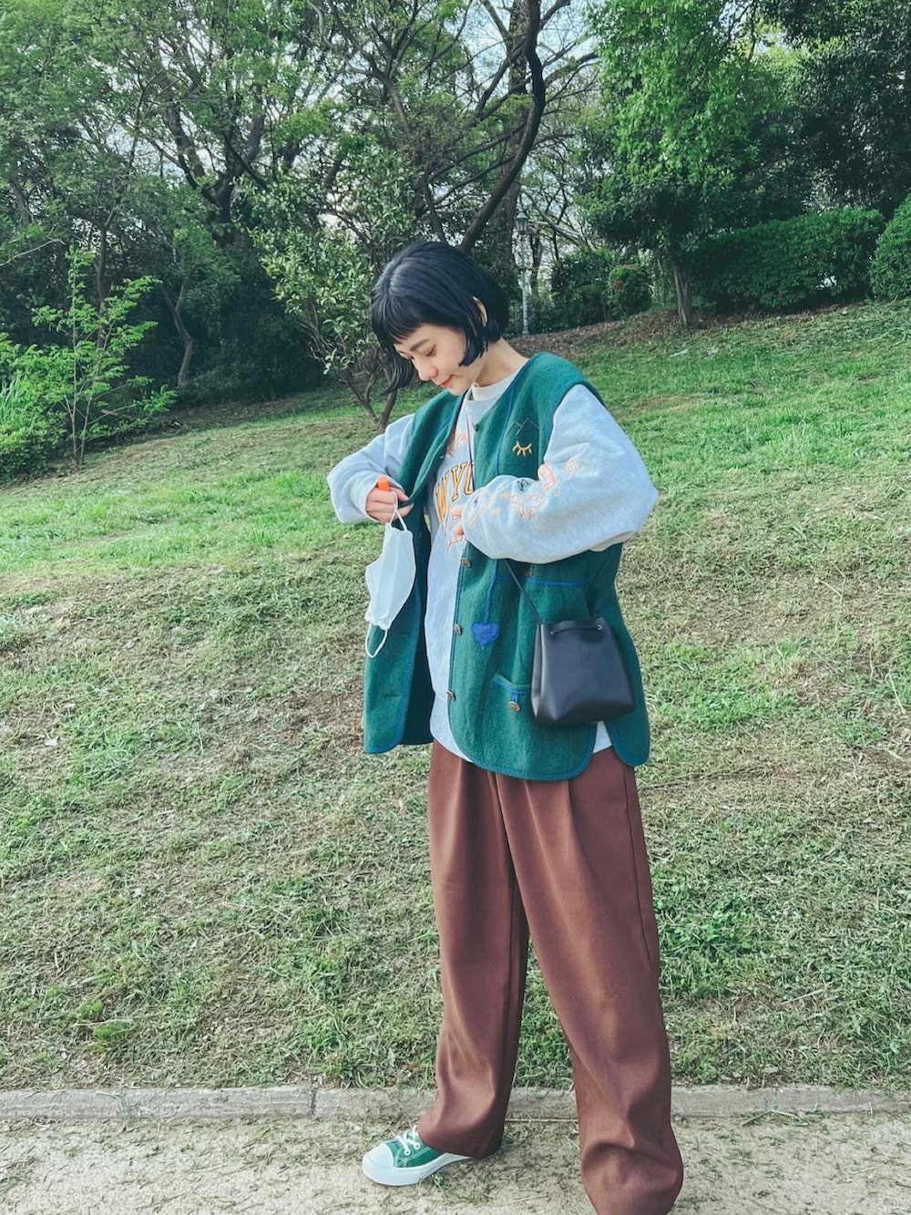 ホワイト系のスウェット、グリーン系のベスト、ブラック系のショルダーバッグを着用したレディースの春コーディネートの2枚目の写真