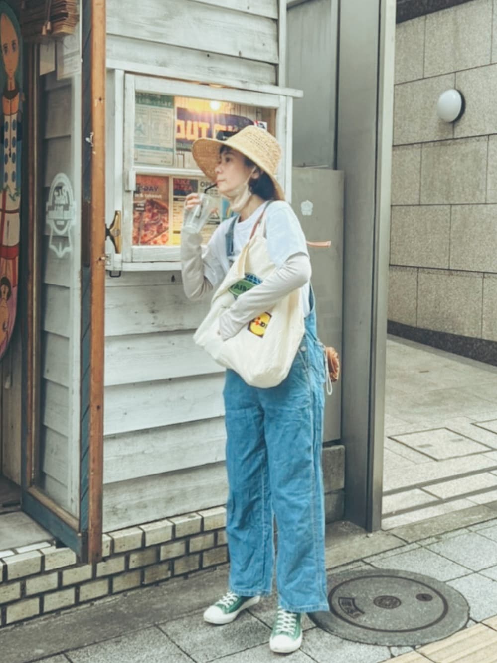 ブルー系のサロペット/オーバーオール、グリーン系のスニーカー、ベージュ系のハットを着用したレディースの夏コーディネートの2枚目の写真