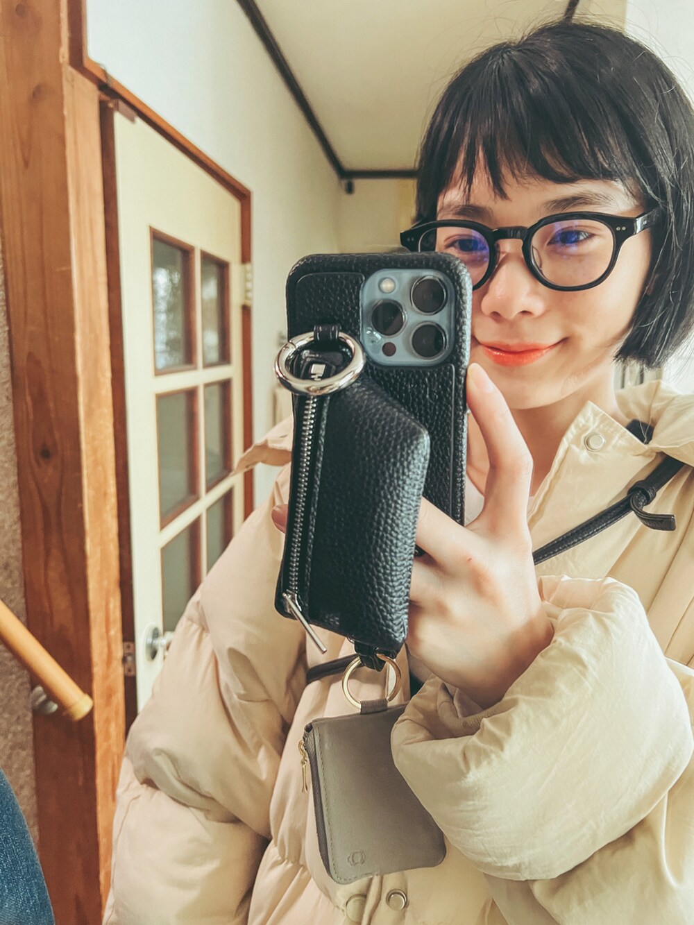 ホワイト系のダウンジャケット/コート、ブラック系のオールインワン・サロペット、ブラック系のメガネを着用したレディースの冬コーディネートの3枚目の写真