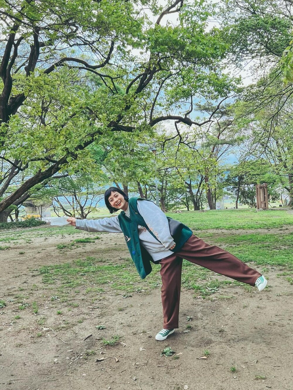 ホワイト系のスウェット、グリーン系のベスト、ブラック系のショルダーバッグを着用したレディースの春コーディネートの3枚目の写真