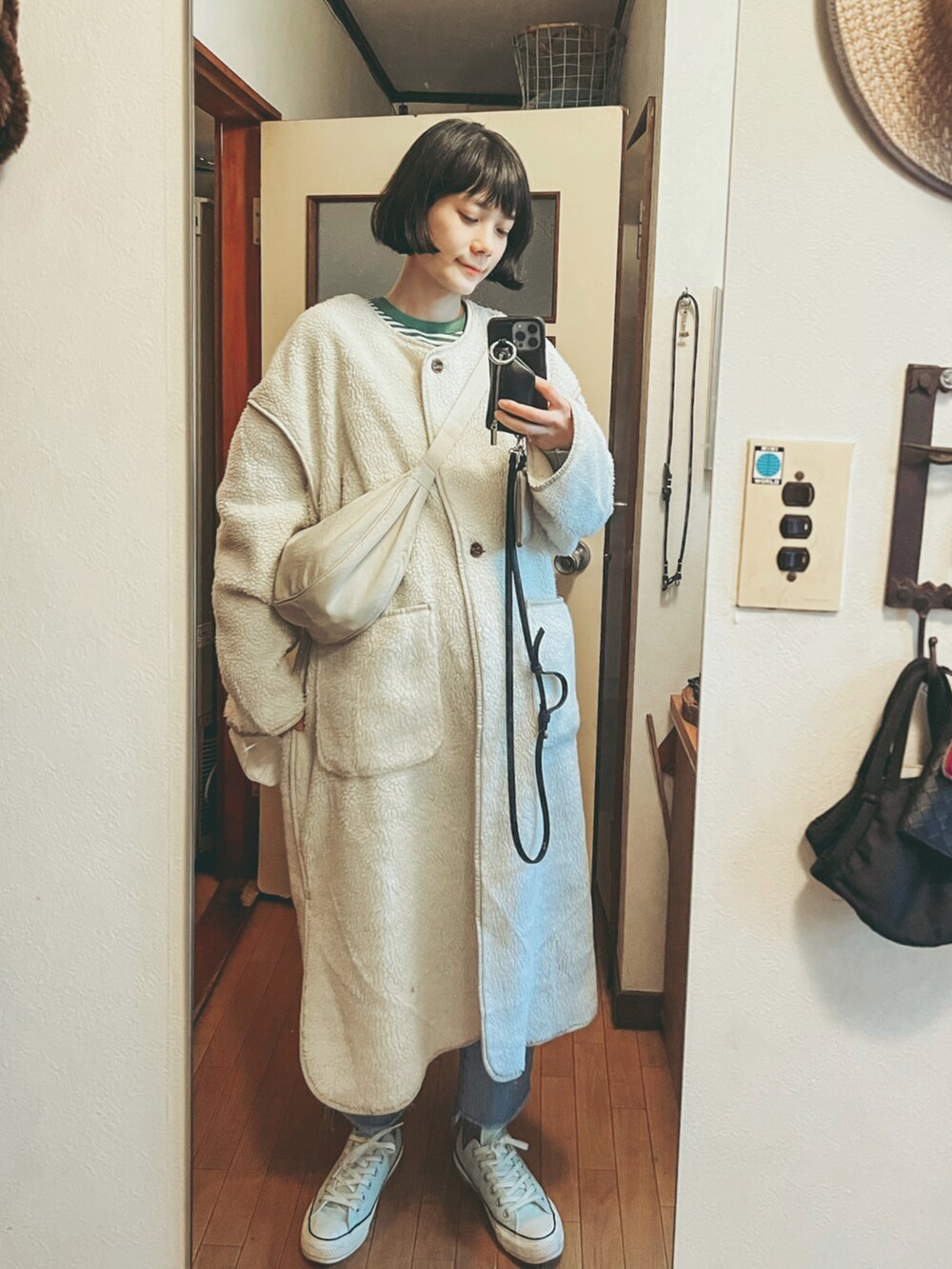 グリーン系のTシャツ/カットソー、ホワイト系のムートンコート、ホワイト系のボディバッグ/ウエストポーチを着用したレディースの春コーディネートの2枚目の写真