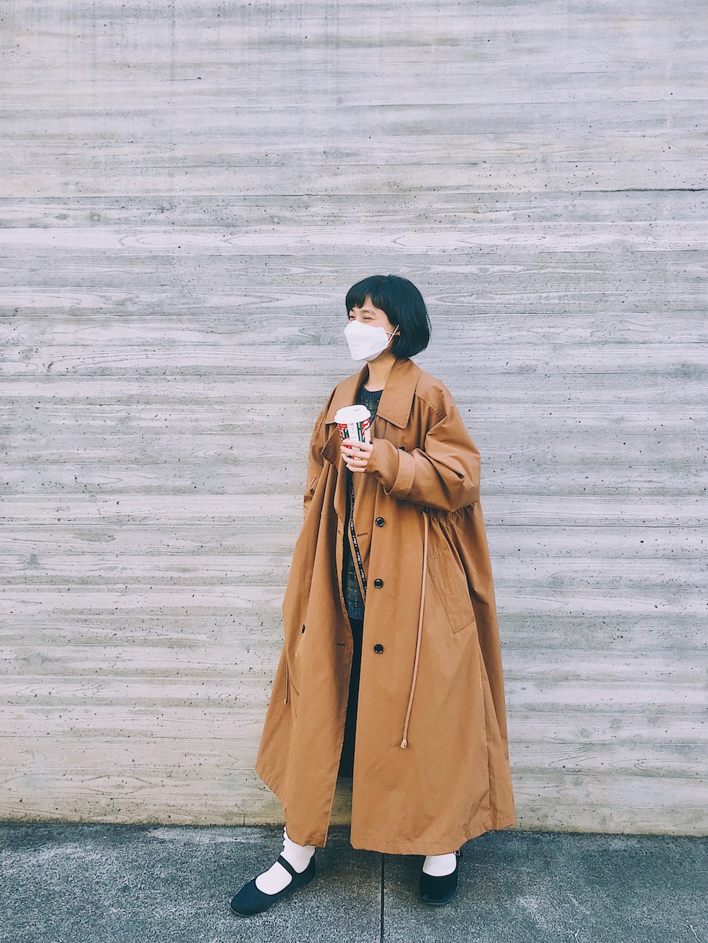 ブラウン系のトレンチコート、ブルー系のニット/セーター、ブラック系のバレエシューズを着用したレディースの秋コーディネートの2枚目の写真