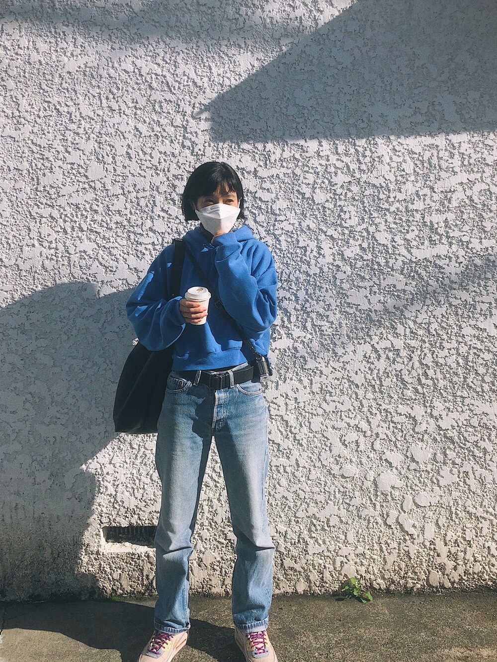 ブルー系のパーカー、ブルー系のデニムパンツ、ブラック系のショルダーバッグを着用したレディースの冬コーディネートの2枚目の写真