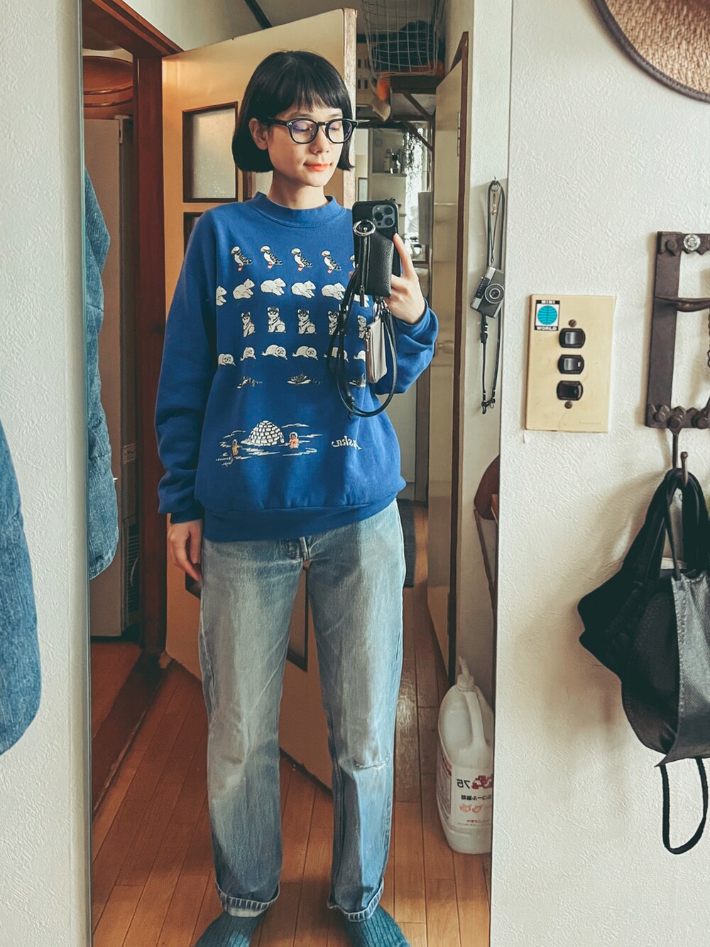 ブルー系のスウェット、ブルー系のデニムパンツ、ブラック系のスマホケース/カバーを着用したレディースの冬コーディネートの2枚目の写真