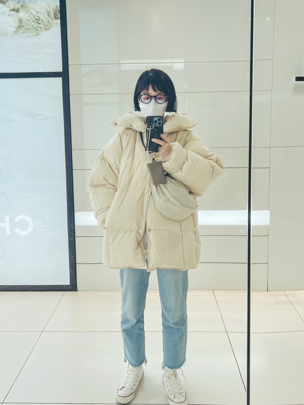 ホワイト系のダウンジャケット/コート、ブルー系のデニムパンツ、ホワイト系のスニーカーを着用したレディースの冬コーディネートの3枚目の写真