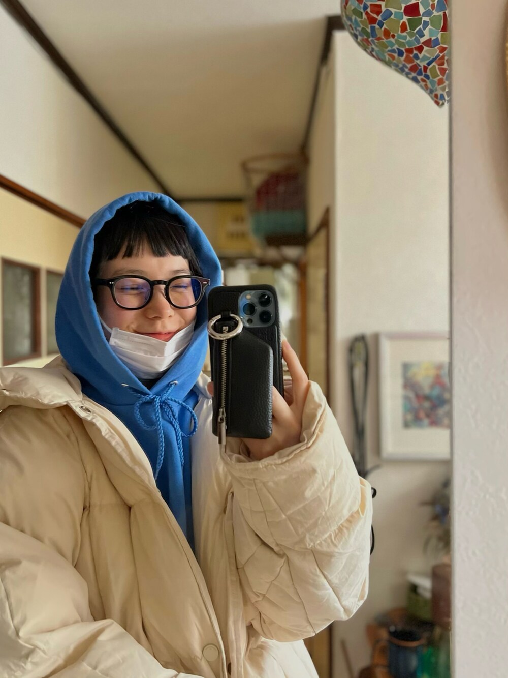 ブルー系のパーカー、ホワイト系のダウンジャケット/コート、ブラック系のスマホケース/カバーを着用したレディースの冬コーディネートの2枚目の写真