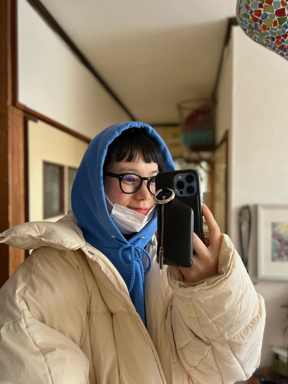 ブルー系のパーカー、ホワイト系のダウンジャケット/コート、ブラック系のスマホケース/カバーを着用したレディースの冬コーディネートの3枚目の写真