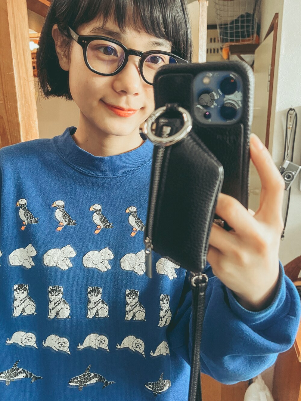 ブルー系のスウェット、ブルー系のデニムパンツ、ブラック系のスマホケース/カバーを着用したレディースの冬コーディネートの3枚目の写真