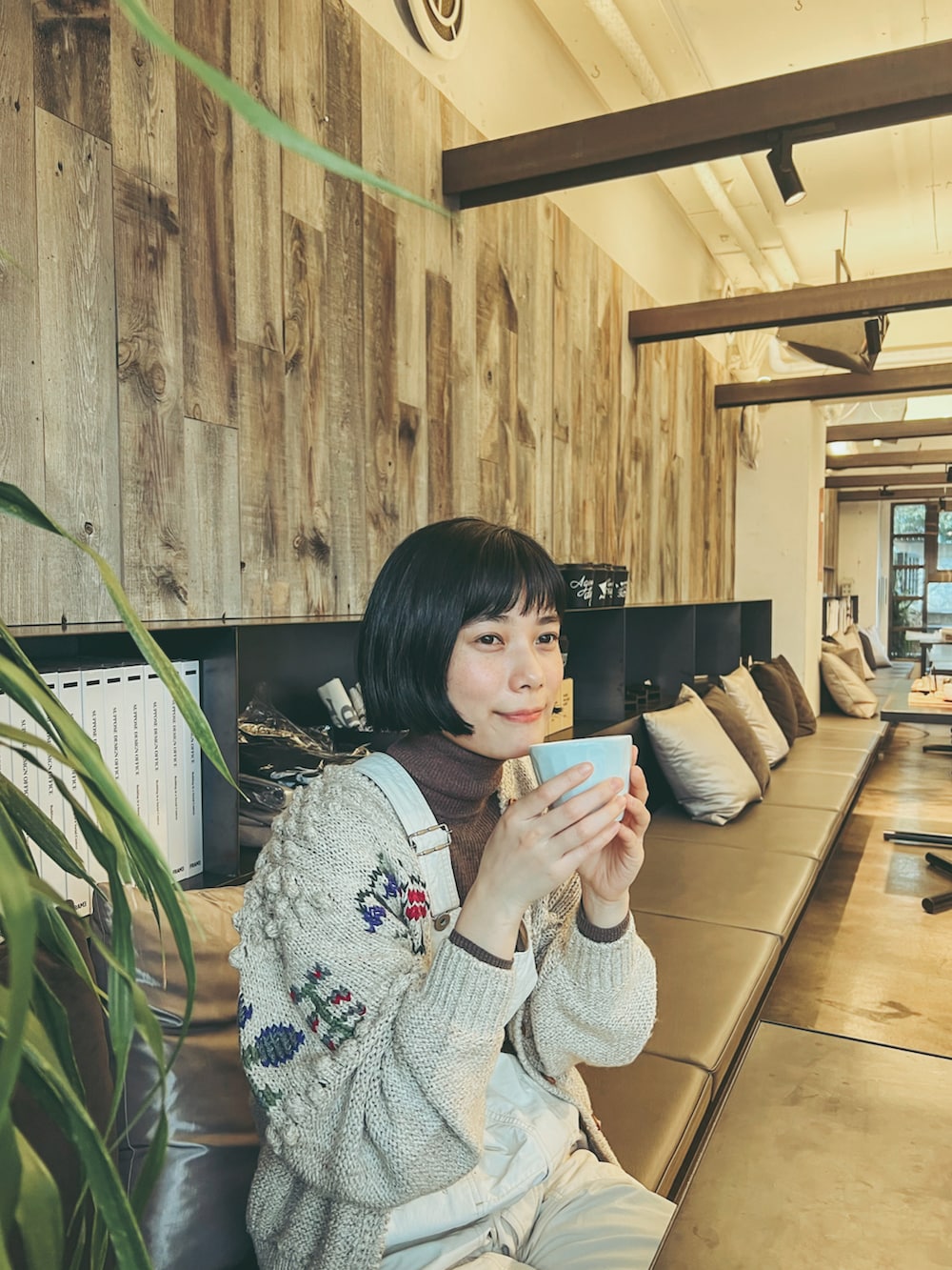 ホワイト系のサロペット/オーバーオール、ベージュ系のカーディガン/ボレロ、ブラック系のブーツを着用したレディースの冬コーディネートの2枚目の写真