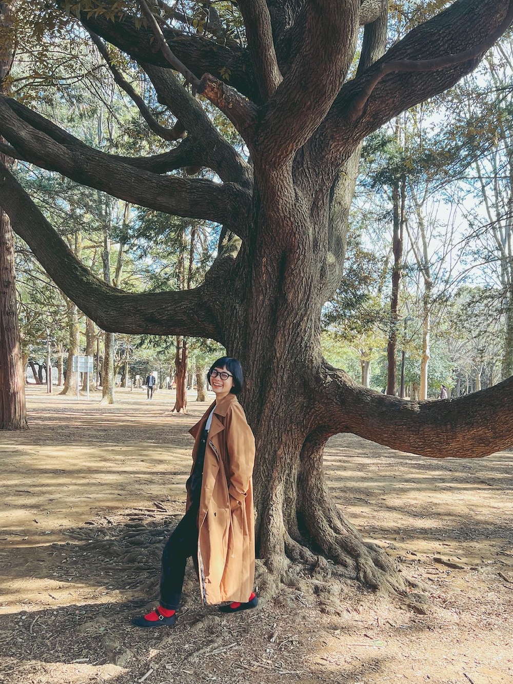 ベージュ系のトレンチコート、ブラック系のオールインワン・サロペット、ホワイト系のスウェットを着用したレディースの春コーディネートの3枚目の写真