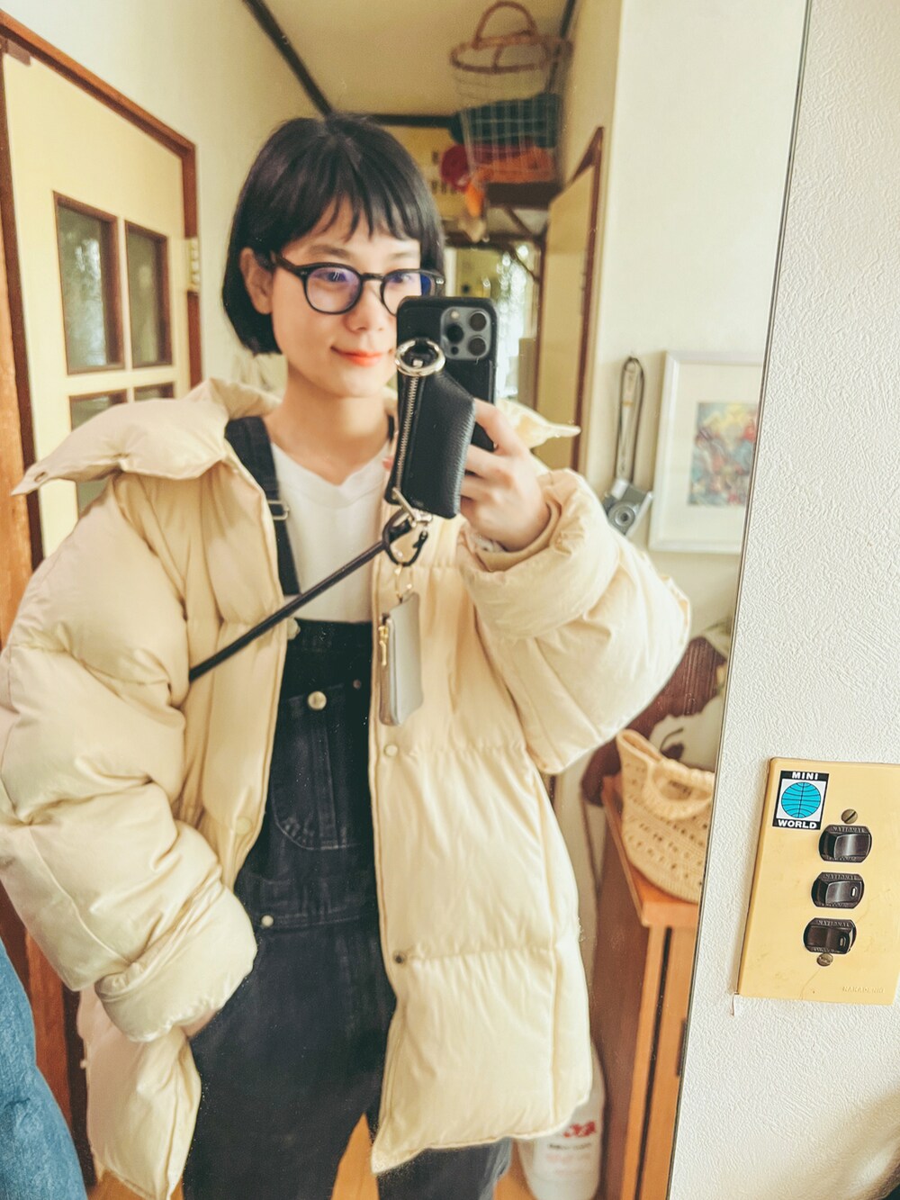 ホワイト系のダウンジャケット/コート、ブラック系のオールインワン・サロペット、ブラック系のメガネを着用したレディースの冬コーディネートの2枚目の写真