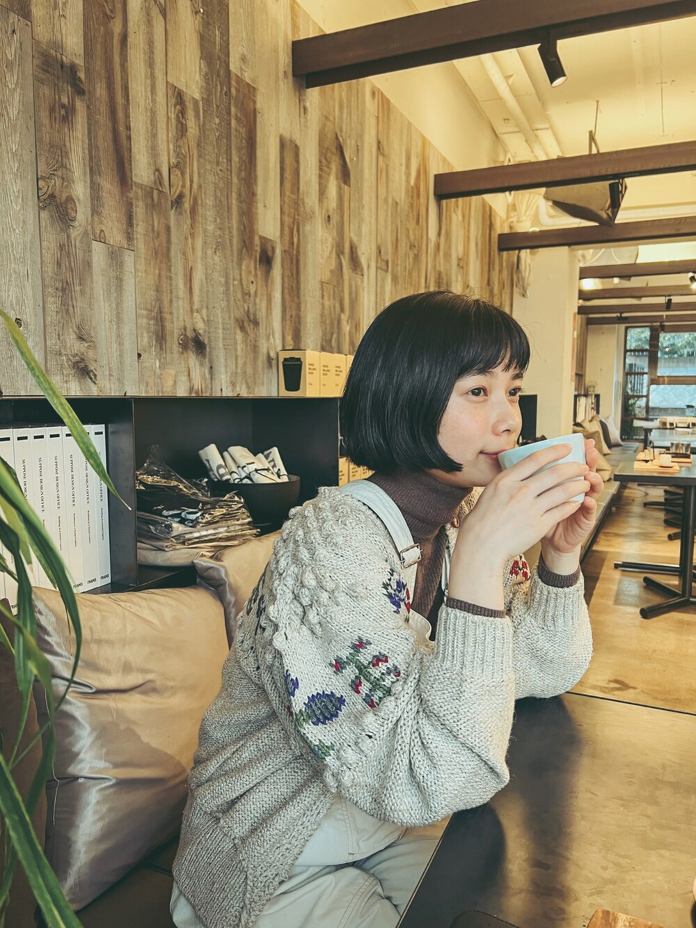 ホワイト系のサロペット/オーバーオール、ベージュ系のカーディガン/ボレロ、ブラック系のブーツを着用したレディースの冬コーディネートの3枚目の写真