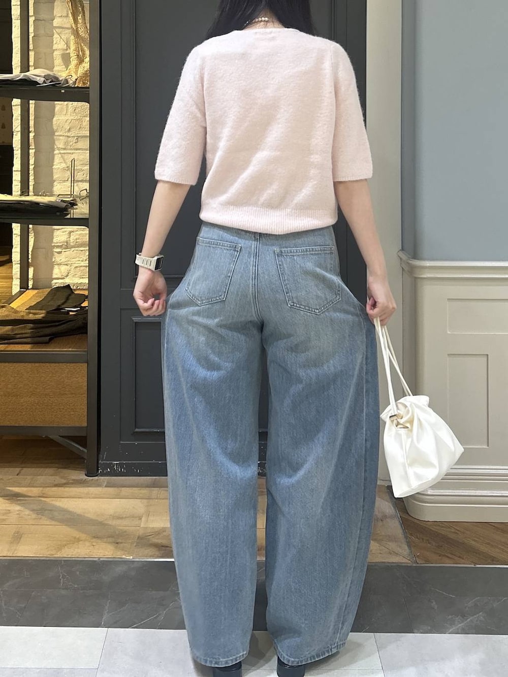 ホワイト系のショルダーバッグ、ブルー系のデニムパンツ、ブラック系のパンプスを着用したレディースの秋コーディネートの4枚目の写真