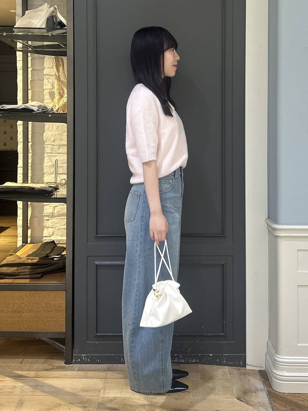 ホワイト系のショルダーバッグ、ブルー系のデニムパンツ、ブラック系のパンプスを着用したレディースの秋コーディネートの2枚目の写真