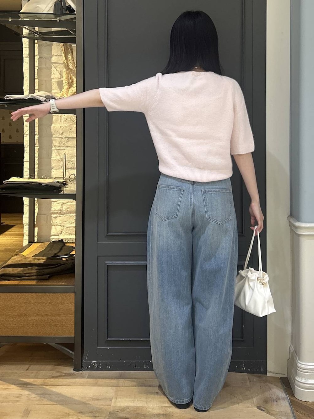 ホワイト系のショルダーバッグ、ブルー系のデニムパンツ、ブラック系のパンプスを着用したレディースの秋コーディネートの3枚目の写真