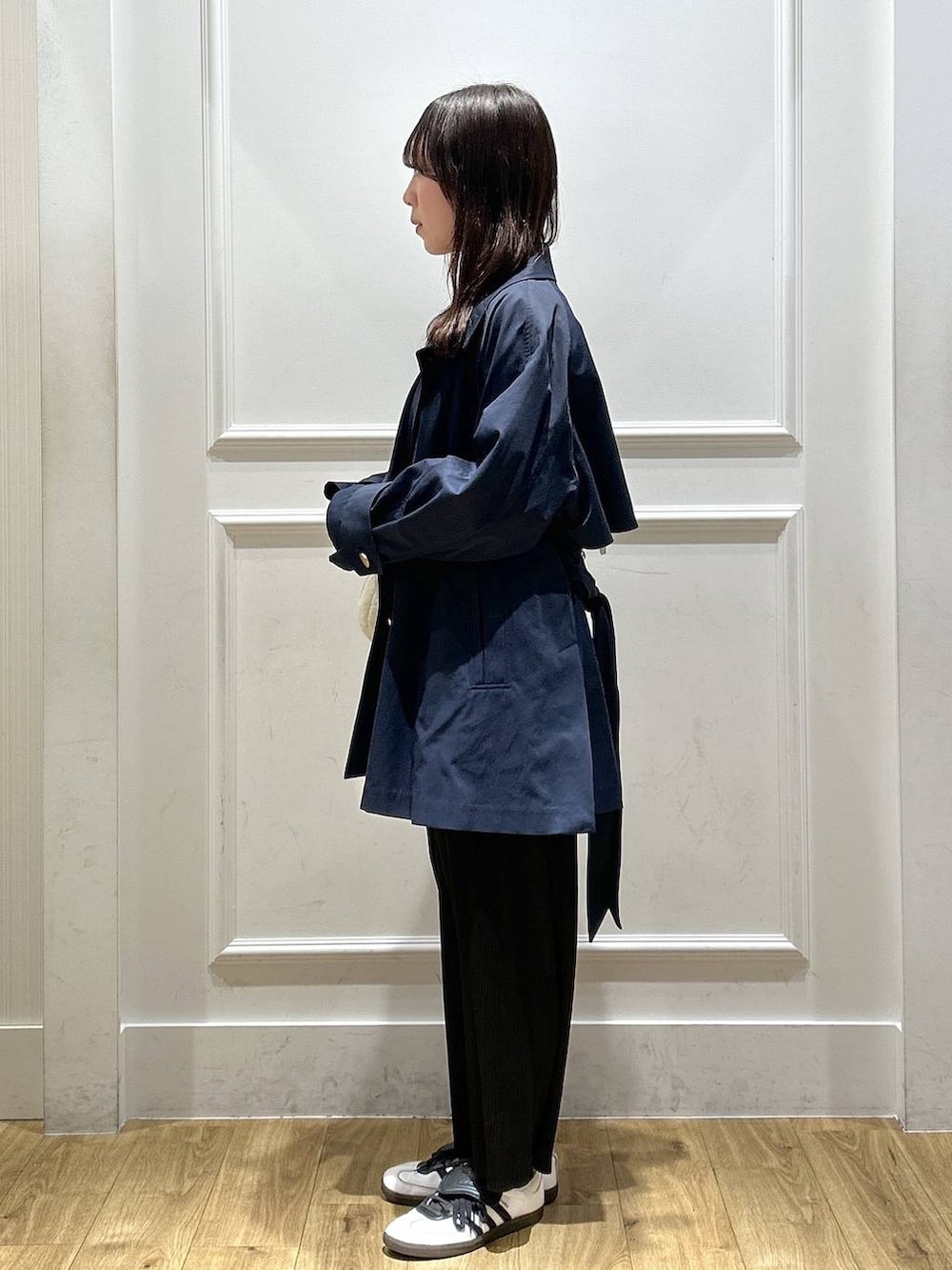 ブラック系のスカート、ホワイト系のTシャツ/カットソー、ブルー系のトレンチコートを着用したレディースの春コーディネートの2枚目の写真